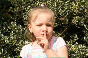 little girl with finger to lips